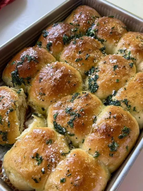 Tray of soft glazed rolls with herbs and flaky salt